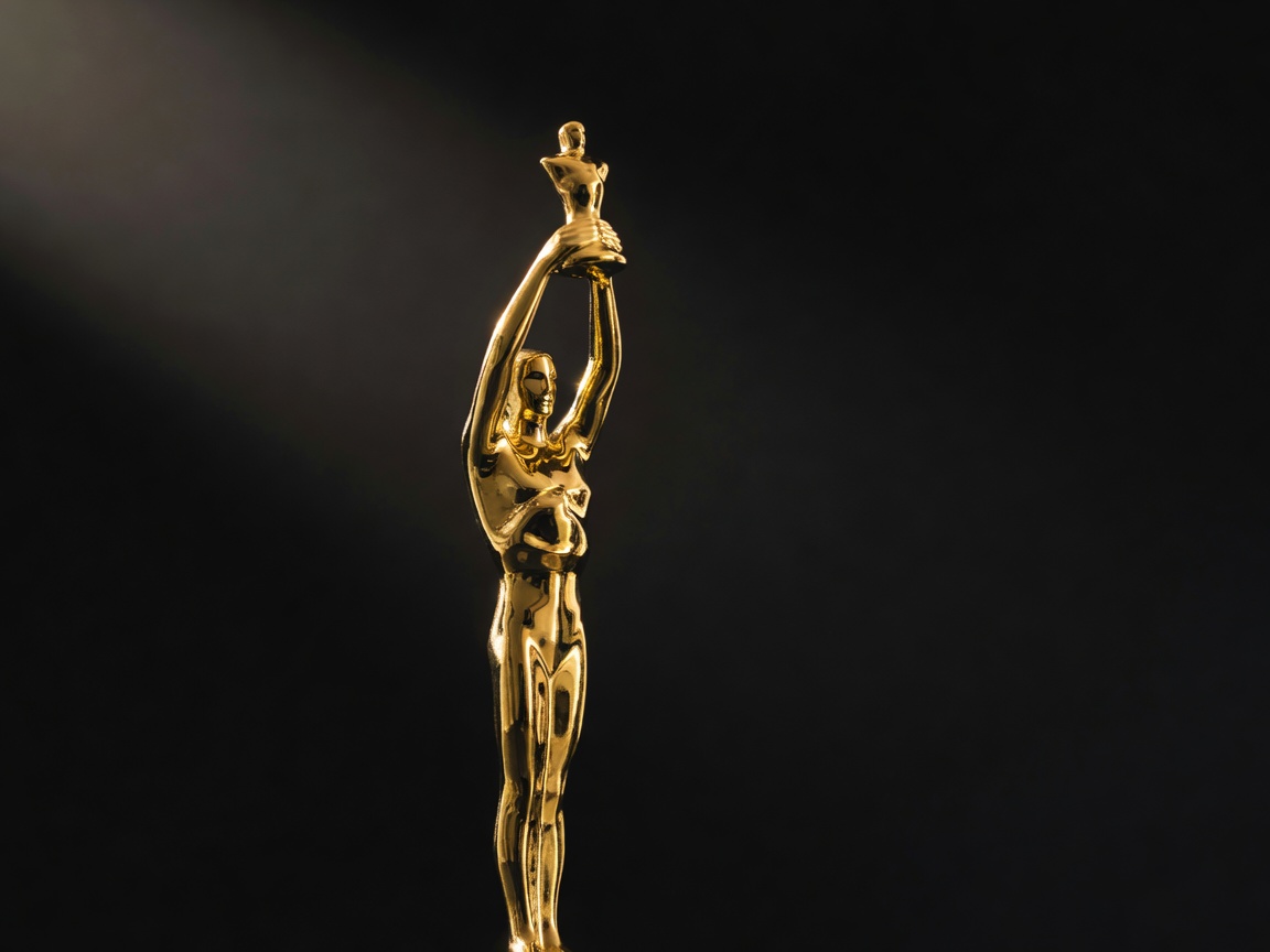Golden award statuette illuminated against black background